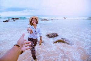 amantes asiáticos feliz viaje naturaleza en la playa. Pareja corriendo en una playa de arena.viajar relajarse en verano. foto