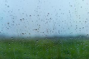 It's raining outside and a raindrop falls on the glass window. photo