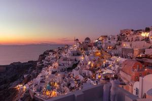 Sunset at the Island Of Santorini Greece, beautiful whitewashed village Oia with church and windmill during sunset, streets of Oia Santorini during summer vacation at the Greek Island photo