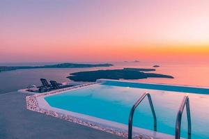 Infinity pool on the rooftop at sunset in Santorini Island, Greece. Beautiful poolside and sunset sky. Luxurious summer vacation and holiday concept, romantic scenery and evening view