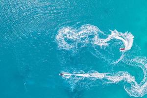 Aerial drone top view of jet skis cruising in turquoise ocean lagoon blue sea. Summer sport recreational outdoor activity, top view photo
