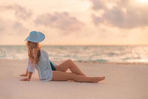 Summer holiday fashion concept - tanning woman wearing sun hat at the beach on a white sand shot from above photo