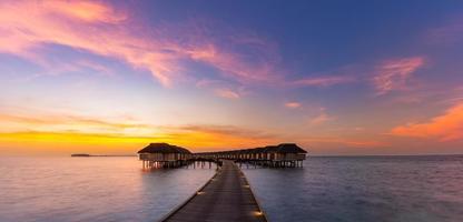 Amazing sunset panorama at Maldives. Luxury resort villas seascape with soft led lights under colorful sky. Beautiful twilight sky and colorful clouds. Beautiful beach background for vacation holiday photo