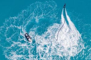 Aerial view of water extreme action sport, summer sea, close to luxury tropical resort . Fly board in ocean lagoon, freedom fun as summer recreational activity. Flyboard view from drone photo