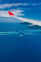 Maldives islands top view from airplane window with airplane's wing photo