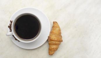 taza de café expreso con croissant por la mañana. foto