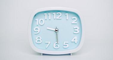 lapso de tempo, o despertador azul mostra a passagem do tempo. das nove às três horas. no fundo branco. video