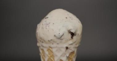 Vista frontal, de cerca, fusión de galletas de helado y crema en el cono. la textura del helado después de derretirse fluye del cono. sobre el fondo negro.
