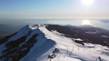 volando sobre los picos nevados de las montañas y el lago en invierno video