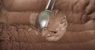 vista de cima, bolas de sorvete colocadas na superfície do chocolate. bolas de sorvete de chocolate recolhidas por uma colher. video