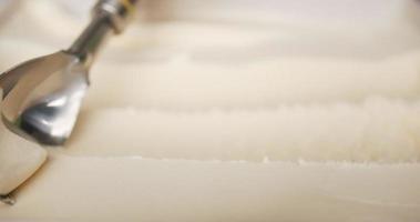 close-up, rolando sorvete de baunilha com uma colher. a textura do sorvete quando ele endurece. video