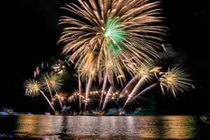 Amazing beautiful colorful fireworks display on celebration night, showing on the sea beach with multi color of reflection on water photo