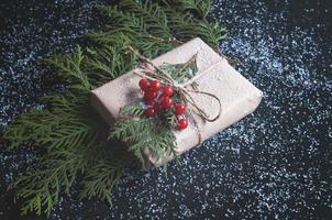 caja de regalo vintage con ramitas de abeto y frutos rojos en una pizarra. foto