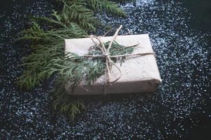 One gift is wrapped in dark black paper with sprigs of fir. photo