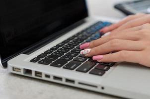 mujer de cerca la mano usando un teclado de computadora portátil. concepto de negocio de tecnología foto