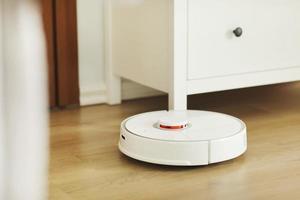 Robot vacuum cleaner performs automatic cleaning of the apartment at a certain time. white robot vacuum cleaner. home cleaning. Smart home. selective focus photo