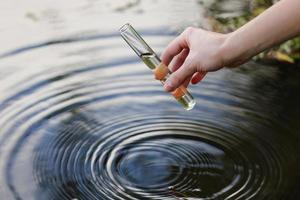 muestra de agua. mano recoge agua para explorar. concepto: análisis de la pureza del agua, medio ambiente, ecología. pruebas de agua para detectar infecciones, permiso para nadar. enfoque selectivo, lugar para el texto. foto