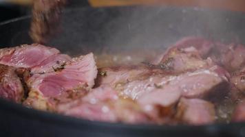 deliciosa carne de res jugosa cocinar en sartén con hierbas sazonadas. video
