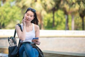 Beautiful asian tourist woman reading the travel guide book searching for for tourists sightseeing spot. Vacation travel in summer. photo