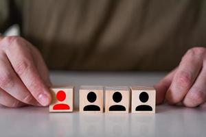 Businessman shows a wooden cube with an employee team icon. photo
