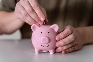 Businessman putting coin into small piggy bank photo