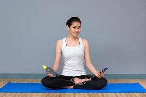 Young asian woman enjoy the music before practicing yoga at yoga healthy sport gym, yoga and meditation have good benefits for health. Photo concept for Yoga Sport and Healthy lifestyle