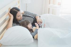 familia amorosa feliz, madre joven asiática viendo dibujos animados en tableta inteligente con su hija en la habitación de los niños. diseño de fotos para la familia, los niños y el concepto de gente feliz.