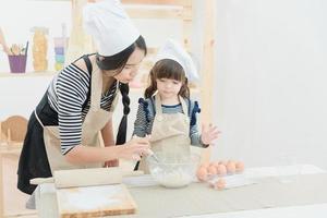 Madre asiática y su hija están preparando la masa para hacer un pastel en la sala de la cocina de vacaciones.Serie de fotos del concepto de familia feliz.