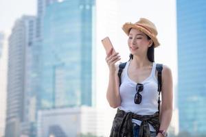 Hermosa mujer turista asiática mirando el teléfono móvil para buscar la ubicación del hito. viajes de vacaciones en verano foto