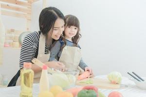 Happy loving family asian mother and her daughter prepare healthy food salad in kitchen room.Photo design for family, kids and happy people concept. photo