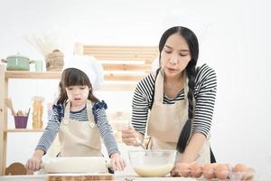 Madre asiática y su hija están preparando la masa para hacer un pastel en la sala de la cocina de vacaciones.Serie de fotos del concepto de familia feliz.