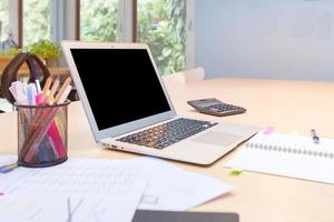 Computadora portátil moderna e inteligente con pantalla en blanco en la mesa de madera en el espacio de trabajo conjunto, nuevo estilo de oficina de trabajo para emprendedores y autónomos foto