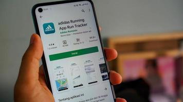 adidas corriendo. aplicación ejecutar la aplicación de Android rastreador. el icono de la aplicación en el primer plano de la pantalla del móvil se sostiene con la mano. foto