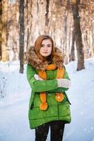 Beautiful young girl in a winter forest. Winter portrait of women dressed in mittens and scarf photo
