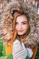 Beautiful young girl in a winter forest. Winter portrait of women dressed in mittens and scarf
