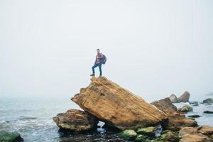 Traveler man stands on a rock on background a beautiful sea