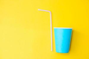 Blue paper cups with drinking colored plastic straws on yellow background. Set for party. Top view. Minimalist Style. Copy, empty space for text photo