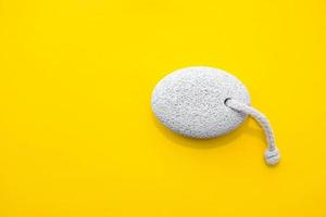 Natural pumice stone with white rope on yellow background. Pedicure and spa concept. Pumice stone for bathroom. Top view. Minimalist Style. Copy, empty space for text
