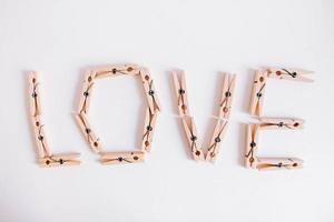 Wooden clothespins on a white background with the inscription the word love. View from above photo