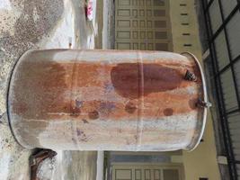 old water barrel that has started to rust in the yard photo