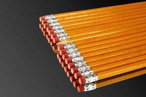 A row of pencils with one exception of a sharp one turning its head against the direction of the rest. photo