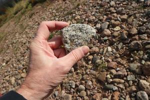 white granite stone with gray splashes in a human hand close-up photo