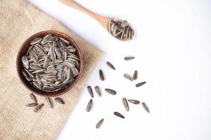 Sunflower seeds in a wooden bowl on a white table photo