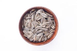 Sunflower seeds in a wooden bowl on a white table photo