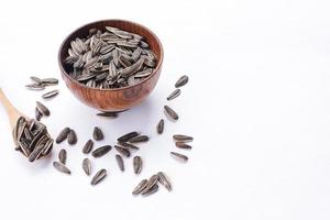 Sunflower seeds in a wooden bowl on a white table photo