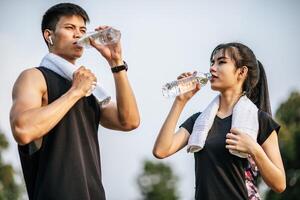 hombres y mujeres se ponen de pie para beber agua después del ejercicio. foto