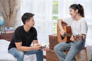 una mujer sentada toca la guitarra y un hombre sosteniendo un libro y cantando. foto