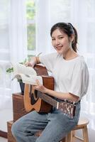 la niña está sentada y tocando la guitarra en la silla. foto