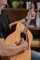 A man sitting and playing guitar on a chair. photo