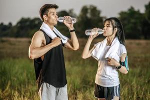Men and women stand to drink water after exercise. photo